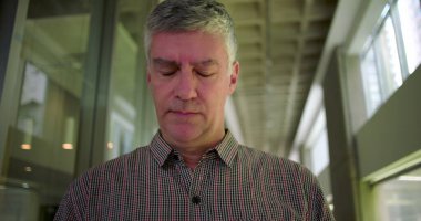 Ofis koridorunda orta yaşlı bir adam gergin bir ağızla iş ortamındaki stres anında gözle görülür endişe ve zihinsel meşguliyet gösteriyor.