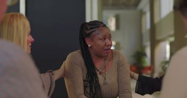 Destek grubu üyeleri ağlayan kadını teselli etmeye çalışıyor. Duygusal çöküntü, empati ve iyileşme camiası ortamında teşvik ile karşılandı.