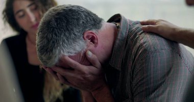 Bir erkek terapi seansı sırasında duygu yoluyla konuşmaya çalışırken diğer bir üye de kırılganlık ve bağlantı anında omuz omuza destek veriyor.