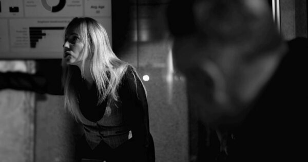 Male employee under intense pressure with head in hand while female boss yells in background, symbolizing emotional strain and accountability in high-stakes office settin