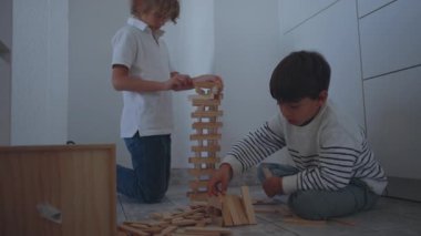 İki çocuk uzun tahta bir kulede birlikte çalışarak, takım çalışmasına, yaratıcılığa, sabra ve sürekli el ele tutuşmaya odaklanmış sıcak bir an oluştururlar.