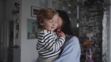 Bir anne bebeğini nazikçe eve taşır, sıcak ve sevgi dolu bir yakınlık ve rahatlık anı yaratır.