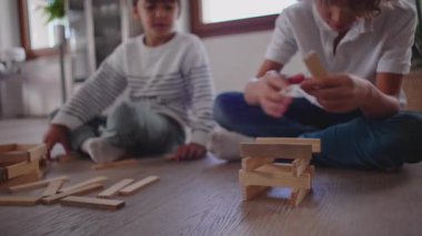 İki çocuk yerde oturup ahşap bir bloğu şekillendiriyor. Sessiz bir konsantrasyonla, neşeli bir yaratıcılık ve nazik bir kardeşlik bağı kuruyorlar.