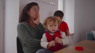 Bebek başparmağına lastik bir bant takar, anne ve büyük kardeş hareket ve merakla dolu eğlenceli bir aile anı oluşturarak onu vurmaya hazırlanırken konsantre olur.