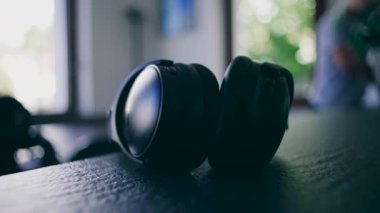 Bir çift kulaklık yumuşak iç mekan ışığında bir masada oturur ve huzurlu bir ev ortamında günlük teknolojinin basit varlığını vurgular.