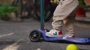 Yürüyen çocuk ayaklarını scooter 'a koyar ve denge ve duruşu keşfederken hareketsiz kalır. Basit arka bahçe oyunlarında erken fiziksel farkındalık ve doğal merakı gösterir.