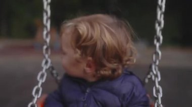 Yürümeye başlayan çocuk kardeşinin arkasından sallanışını izliyor, sonra dikkatini öne çekiyor, salıncaktan çekilmek istediğini işaret ediyor. Oyun oynarken merakı, tereddüdü ve erken iletişimi harmanlayan an..