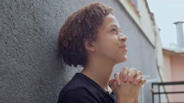 Parlak gökyüzünün altında duvarın karşısında el ele dua ederken nazikçe gülümseyen genç çocuk, çok sadık ve barışçıl bir an.