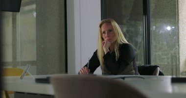 Modern ofis yerinde yalnız başına oturan bir kadın endişeli görünüyor, iş günlerinde bir karar veriyor ya da düşünüyor gibi görünüyor.