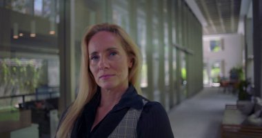 Koridorda dik dik bakan kadın, modern çalışma ortamındaki otorite özgüveni ve özgüvenini dile getiriyor.