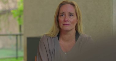 Grup terapisi sırasında duygularıyla konuşan bir kadın derin üzüntü ve hassasiyetini dile getirirken aynı zamanda iyileştirici uzayda destekleyici akranlarıyla iletişim kuruyor.