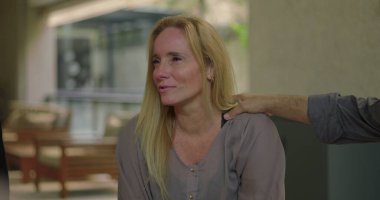 Grup terapi seansında duygusal hikâyeyi paylaşan kadın, erkek grup üyesi güven verici bir şekilde omuz omuza verip, incinebilirliğini gözyaşlarıyla ifade ederken,