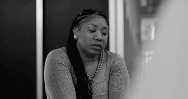 Duygusal rahatlama sonrası sessizlik içinde oturan kadın terapi seansında grup ile birlikte acıyı yansıtıyor.