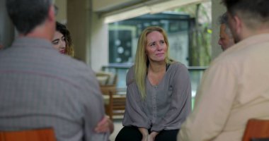 Grup terapisi tartışmasına katılan bir kadın, destek çemberindeki akranlarıyla iletişim kurarken duygusal hassasiyet gösteriyor.