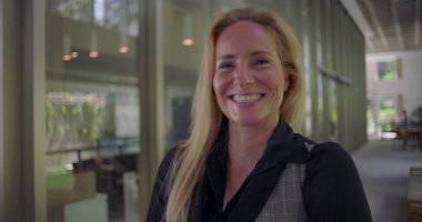 Modern ofis koridorlarında neşe ve açıklıkla gülen bir kadın samimi bir anda pozitif enerji ve otantik duygular yayıyor.