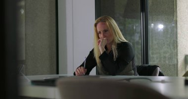 Modern ofis yerinde yalnız başına oturan bir kadın endişeli görünüyor, iş günlerinde bir karar veriyor ya da düşünüyor gibi görünüyor.