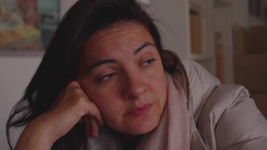 Yansıtıcı bir sükunetle yan tarafa bakan kadın, sessiz bir düşünce anını içinde tutarken yüzünü eline dayayıp dinleniyor.