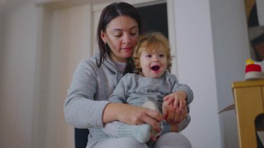 Bakıcı, giyinirken yorgun çocuğu geçindirir, soğukkanlılığını gösterir ve aile içinde günlük yaşantısını sürdürür.