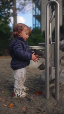 Küçük çocuk, dokunsal keşif odağı ve park ortamında bağımsız keşif yoluyla hareketli oyun alanı özelliklerini gözlemleyerek dönüşüyor