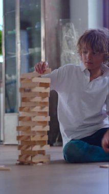 Çocuk, bağımsızlık öğrenme süreçlerini ve oyun zamanı sorunlarını çözme sürecini gösteren yoğun konsantrasyonla düşük blok yapısı inşa ediyor.