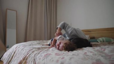 Anne ve küçük çocuk yatakta nazikçe yakınlaşır, rahatlık, duygusal güvenlik, güven ve normal aile hayatı içinde gevşek bir bağ ifade eder.