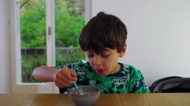 Çocuk sürekli olarak masada mısır gevreği yiyor. Bu da kendini beslemeye odaklandığını ve her gün evde kahvaltı yaptığını gösteriyor.