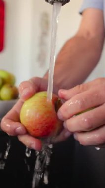 Taze elma musluğun altında durulanır basit hijyen pratiği ev bakımı ve günlük yemek hazırlama anı ifade edilir.