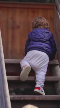 Küçük çocuk, yeni yürümeye başlayan başka bir çocuğu karşılamak için duraklarken tanıma iletişimi ve oyun alanı ortamında ortaya çıkan sosyal etkileşimi ifade ediyor