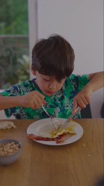 Çocuk yemek yerken tabağa odaklanıyor. Koordinasyon, kişisel bakım ve evde sakin bir sabah rutini uyguluyor.