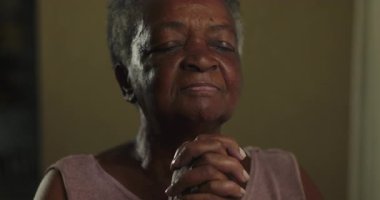 Kıdemli kadın duada el ele tutuşur. İnancını, umudunu, huzurunu ve inancın şekillendirdiği kalıcı iç huzurunu ifade eder.