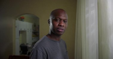 Afrika kökenli Amerikalı bir adam, sakin bir ifadeyle doğrudan kameraya bakıyor ve sessiz bir yansıtıcı portre anı yaratıyor.