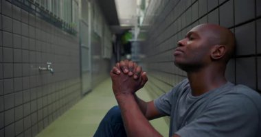 Afro-Amerikalı adam tek başına dua ederken yukarıya bakar, güven, teslimiyet, ruhani yansıma ve kişisel mücadele yoluyla azim ifade eder.