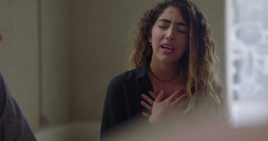 Grup terapisinde konuşurken duygulanan genç kadın, destekleyici ve önyargısız ortamda zor bir deneyim yaşarken gözleri kapalı