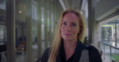 Koridorda dik dik bakan kadın, modern çalışma ortamında otorite güveni ve kendine güveni aktarıyor.