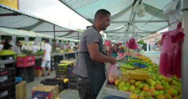 Hispanik satıcı açık hava sokak pazarında ürünleri parayla değiş tokuş ederek insan etkileşimi ve mahalle gıda ticareti yaparak satışını tamamlıyor.
