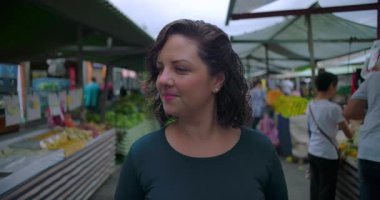 Açık hava pazarı satıcıları arasında yürüyen ve kendine güveni tam bir rutin olan ve yerel halk ticaretiyle uğraşan bir kadın tüketici.