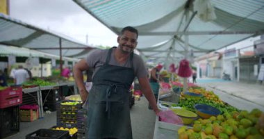 İspanyol satıcı, meyva sergilemenin yanında mahalle pazarında rahatladı. Arkadaşlık, iş kimliği ve toplum bazlı gıda ekonomisi ile olan bağlantısını ifade etti.