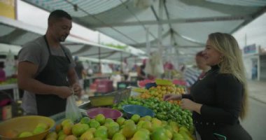 İspanyol sokak satıcısı, bir torba turunçgil satışı yaparak müşteriye rutin alışverişi karşılıklı saygı ve mahalle piyasa hayatına ortak katılımla tamamlıyor.