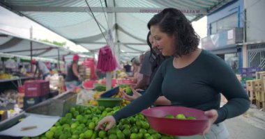 Komşulardan taze narenciye seçen kadın tüketiciler, günlük etkileşim ve toplum temelli sokak piyasa yaşamını oluşturan ortak karar paylaşımı yapan tezgah üretiyor.