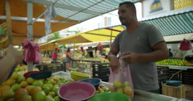 Mahalle pazarında taze ürünleri paketleyen İspanyol satıcı kamu gıda ekonomisinde pratik döviz aşinalığı ve insan ölçeğinde etkileşim sağlıyor.