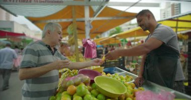 Hispanik tedarikçi, açık hava pazarında kıdemli müşteriye konukseverlik rutin ticaret ve insan ölçekli gıda alışverişini yansıtıyor.