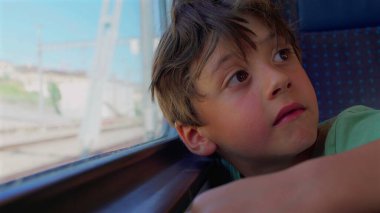 Delikanlı, trenin penceresinden dışarı bakıyor. Geniş gözlü, derin yüzlü, kolları pervazda dinleniyor. Gün ışığında geçen izler gibi bulanık.