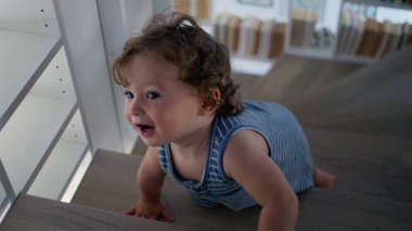 Yürüyen çocuk merdivenlerden odaklanmış bir ifadeyle çıkıyor, küçük eller kitap dolu odada adımları sıkıca tutuyor, ev ortamında bağımsızlığını ve merakını ifade ediyor.