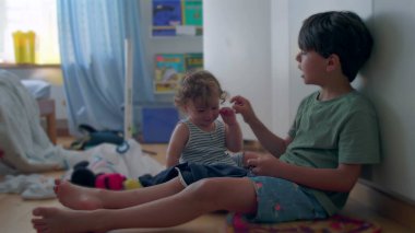 Ağabeyi, çocuk odasında birlikte otururken sürekli yüzüne hafifçe vura vura çocuğa şaklabanlık yapıyor.