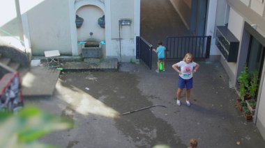 Büyükannesi, çocuğun sokağa girmesini engellemek için sessiz şehir avlusunun kapısını kapatıyor. Çocukların açık havada oynadığı samimi anlarda koruyucu bir jest yapıyor.