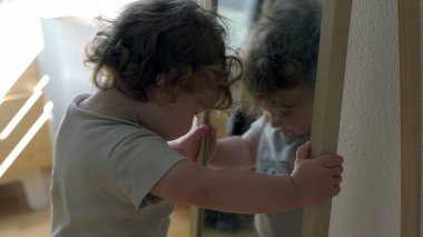 Bebek aynaya tutunarak ve yüzeye yakın eğilerek dengeyi korurken, her gün kapalı alanda keşif ve erken motor geliştirme anı