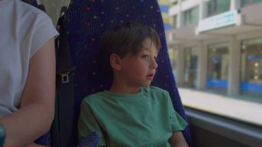 Otobüs koltuğunda oturan genç adam pencereden dışarı bakıyor. Düşünceli bir ifadeyle. Yüzüne doğal bir ışık düşüyor.