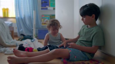 Ağabeyi, çocuk odasında birlikte otururken sürekli yüzüne hafifçe vura vura çocuğa şaklabanlık yapıyor.