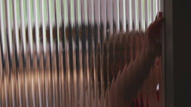 Yürümeye başlayan çocuğun yüzü, tırtıklı yarı şeffaf kapıya, kıvırcık saçlara ve dokulu bariyer yoluyla kafa karışıklığı veya sıkıntı gösteren duygusal ifadeye yakın plan.