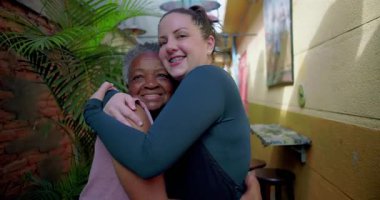 Kadın garson, şefkat, destek, güven ve gerçek insan sıcaklığını günlük hizmet ortamında paylaşan Afrikalı Amerikalı son sınıf öğrencisiyle samimi bir kucaklaşma paylaşıyor.